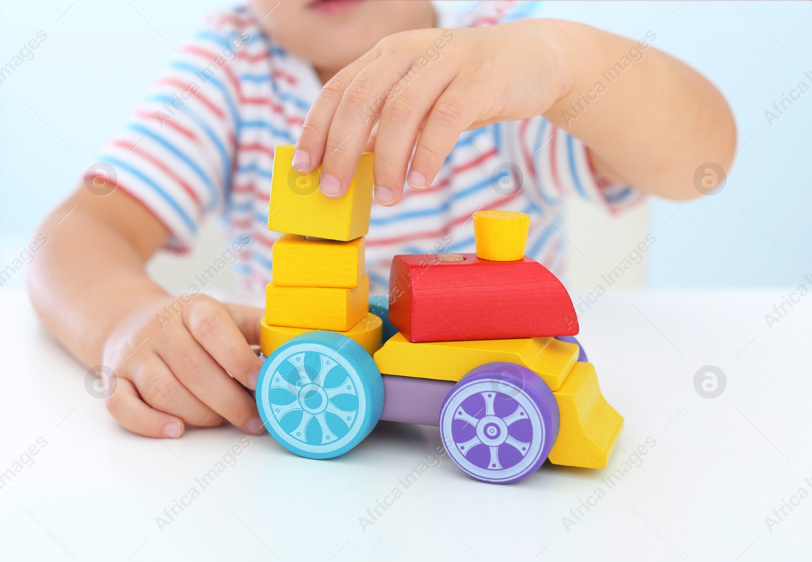 Photo of Little boy playing with toy at white table, closeup