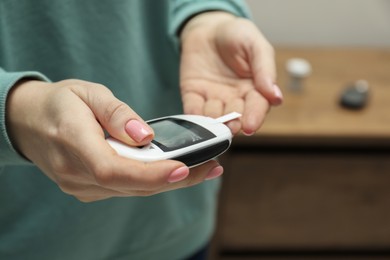 Diabetes. Woman checking blood sugar level with glucometer at home, closeup