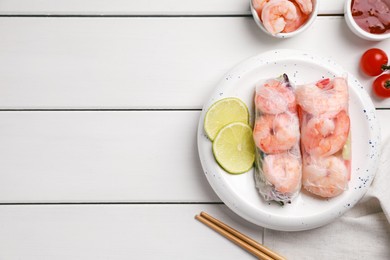 Photo of Delicious spring rolls with shrimps wrapped in rice paper served on white wooden table, flat lay. Space for text