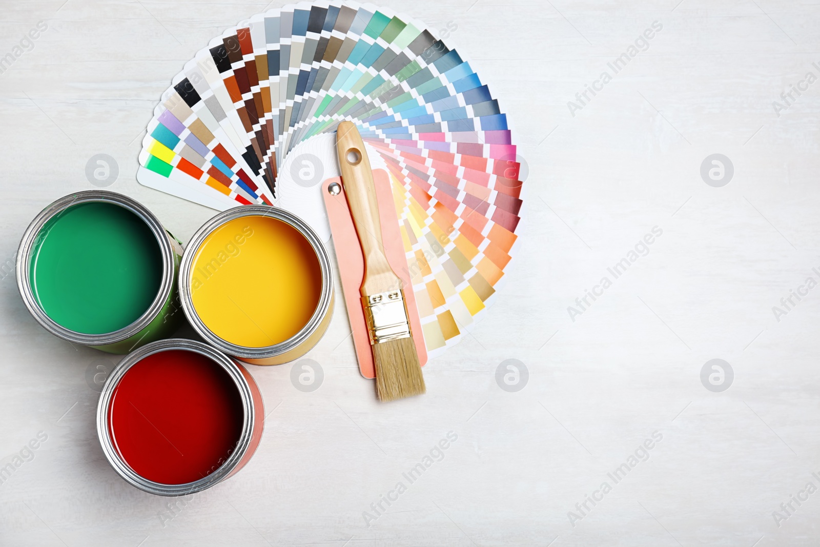 Photo of Cans with paint, brush and color palette on light background, top view. Space for text