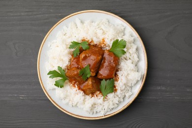 Delicious goulash with rice on grey wooden table, top view