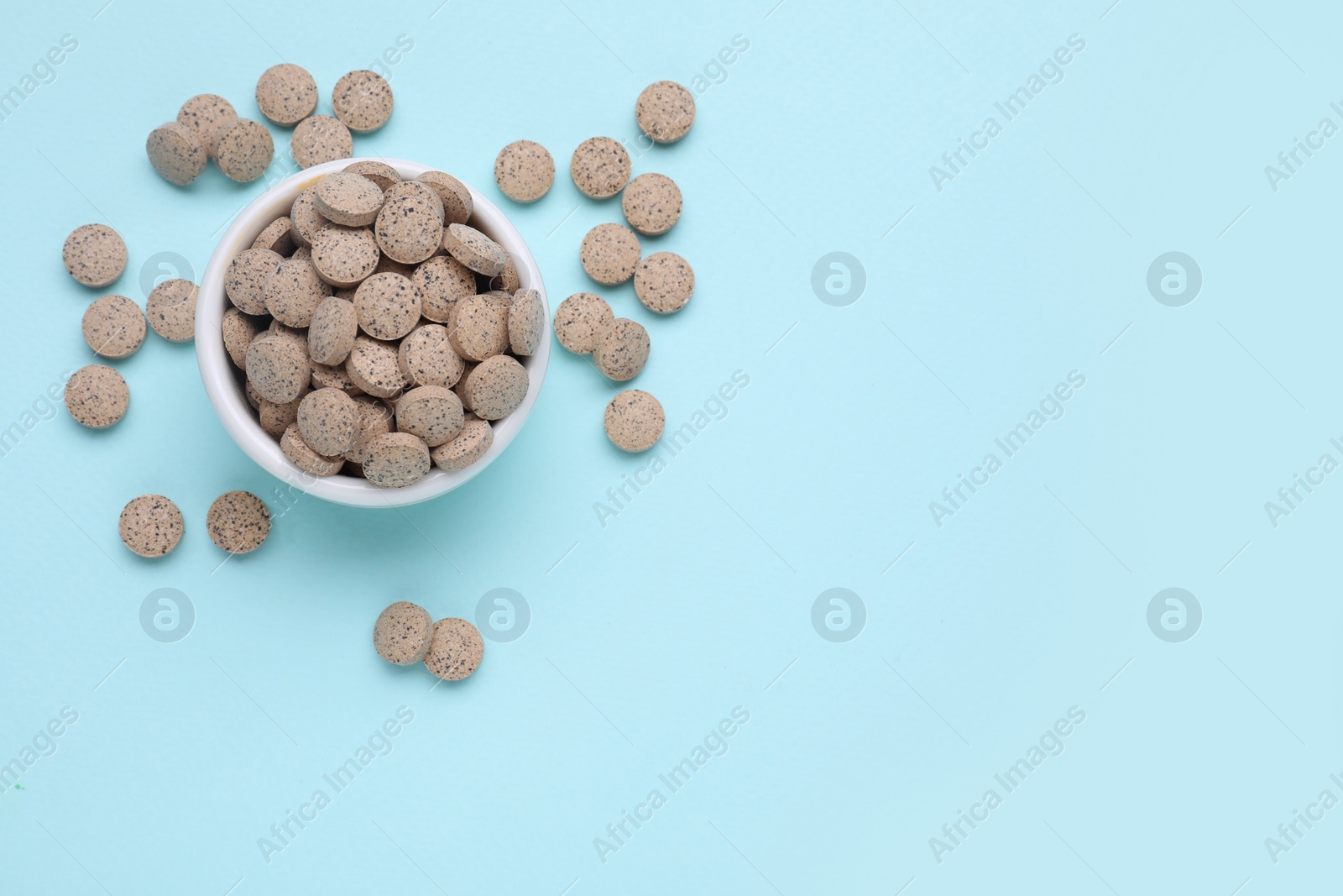 Photo of Beer yeast pills on light blue background, flat lay. Space for text