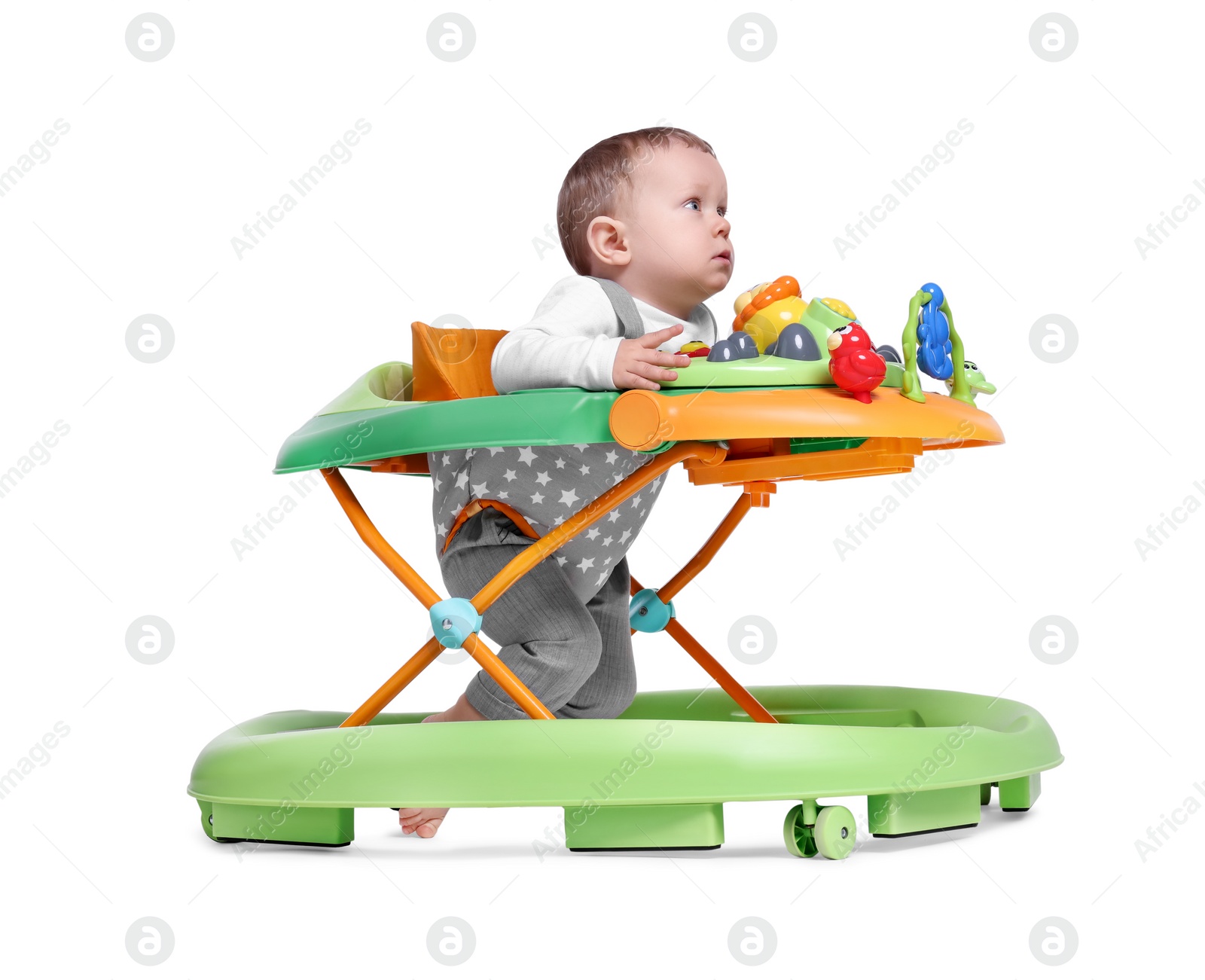 Photo of Cute little boy making first steps with baby walker on white background