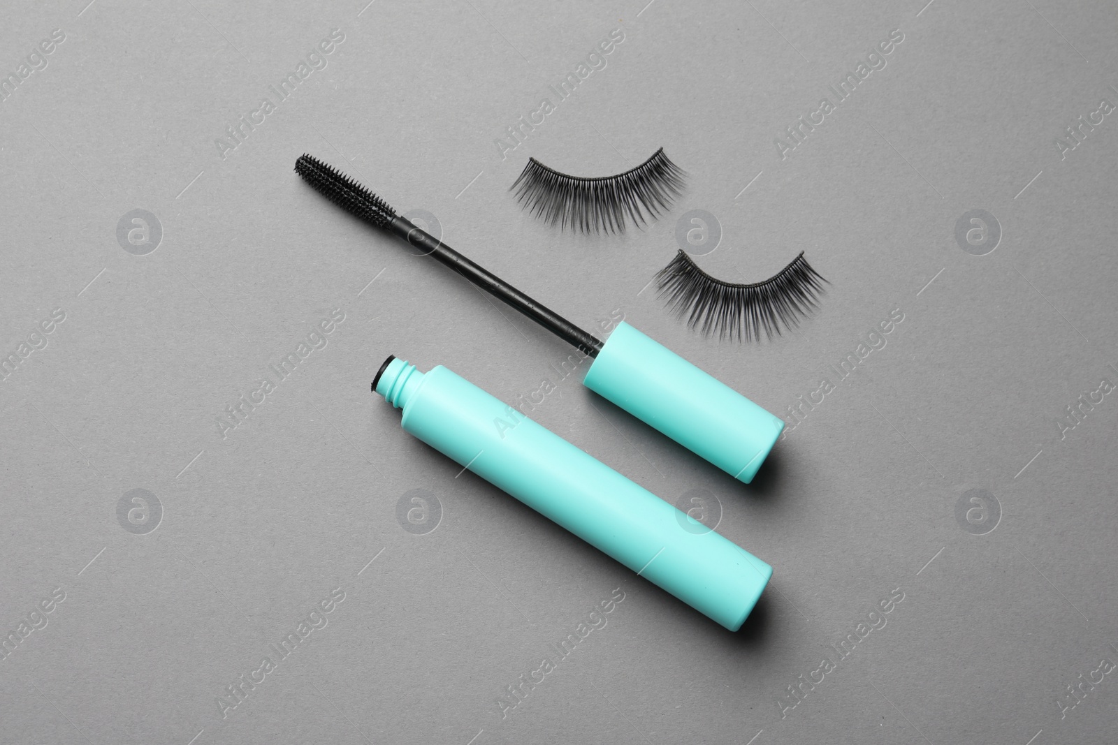 Photo of False eyelashes and mascara on grey background, flat lay