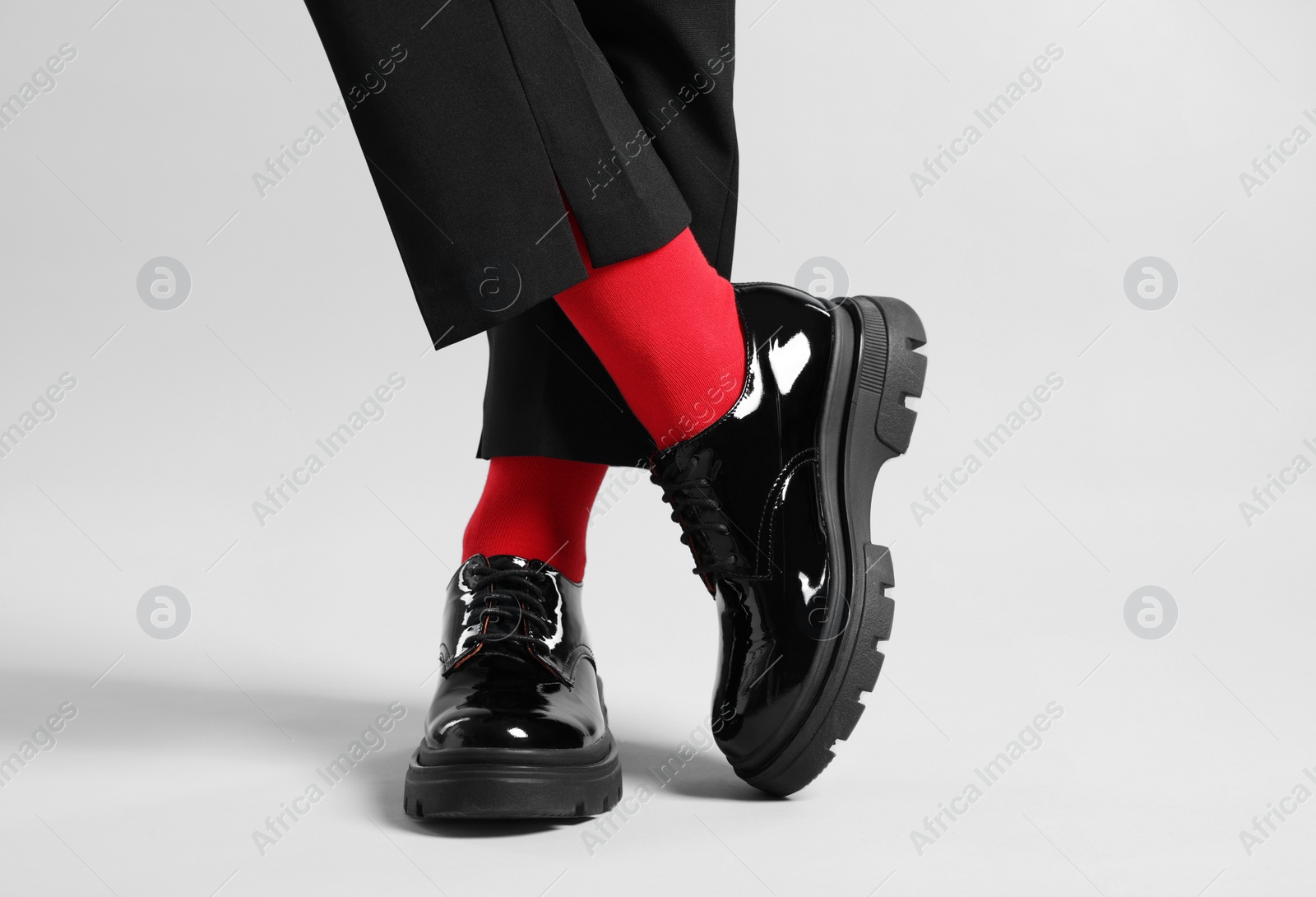 Photo of Woman in pants, shoes and stylish red socks on light grey background, closeup