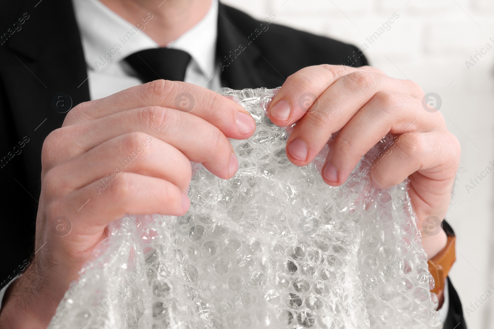 Photo of Businessman popping bubble wrap, closeup view. Stress relief