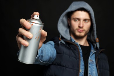 Photo of Handsome man holding used spray paint against black background