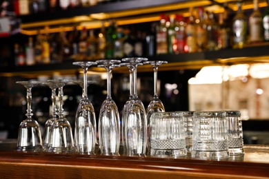 Photo of Different empty clean glasses on counter in bar