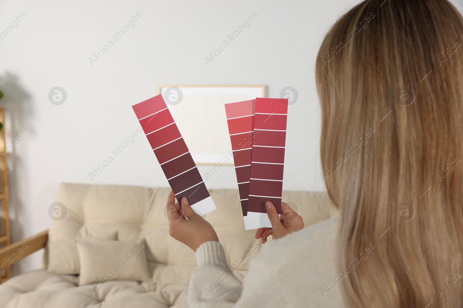 Photo of Woman choosing color for wall in room, focus on hands with paint chips. Interior design