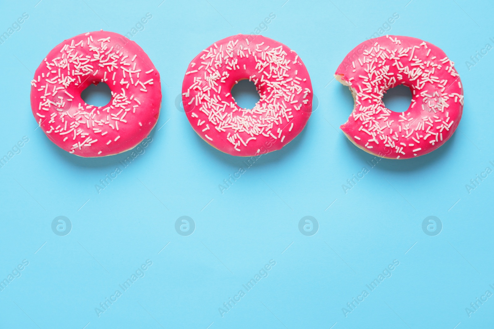 Photo of Delicious glazed doughnuts on color background, top view