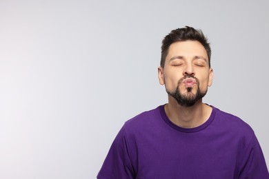 Handsome man blowing kiss on light grey background. Space for text