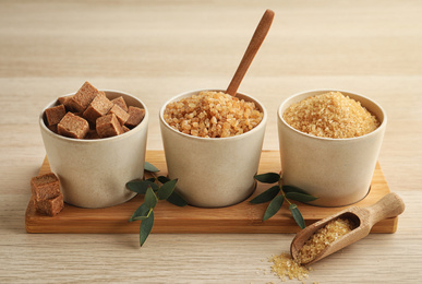 Photo of Bowls with different types of brown sugar on wooden table