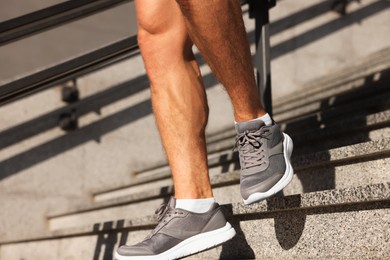 Man running down stairs outdoors on sunny day, closeup