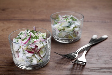 Glass bowls of vegetarian salad with cucumber and onion on table