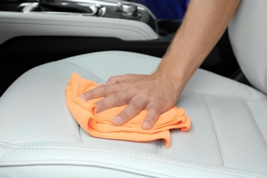Photo of Man washing car seat with rag, closeup