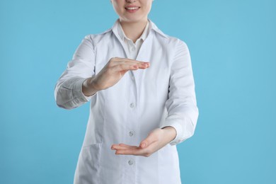 Dental assistant holding something on light blue background, closeup