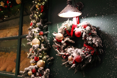 Beautiful Christmas wreath on green wall near window outdoors