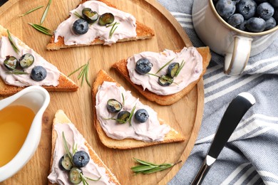 Photo of Tasty sandwiches with cream cheese, honey and berries on wooden tray, flat lay