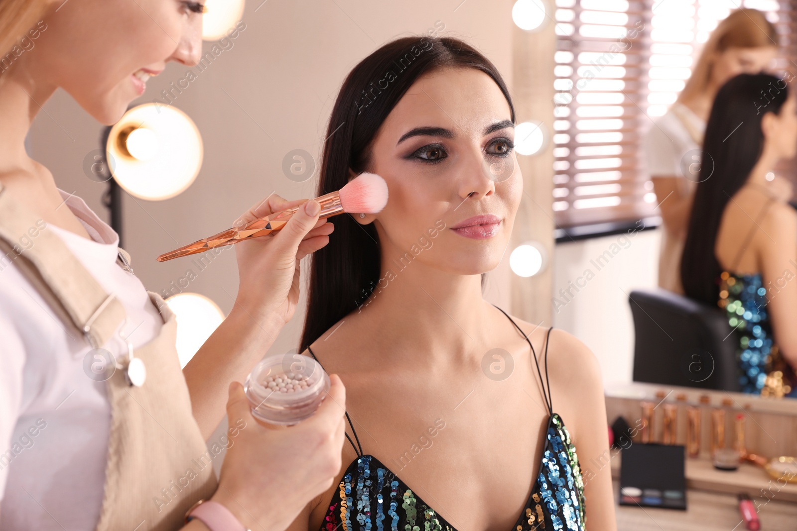 Photo of Professional makeup artist working with beautiful woman in salon