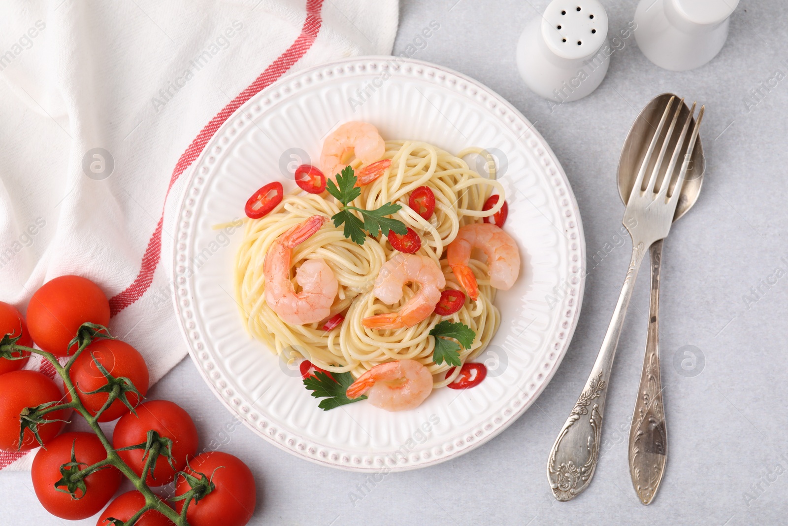 Photo of Tasty spaghetti with shrimps, chili pepper and parsley served on grey table, flat lay