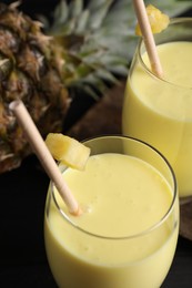 Photo of Tasty pineapple smoothie and fruit on table, closeup