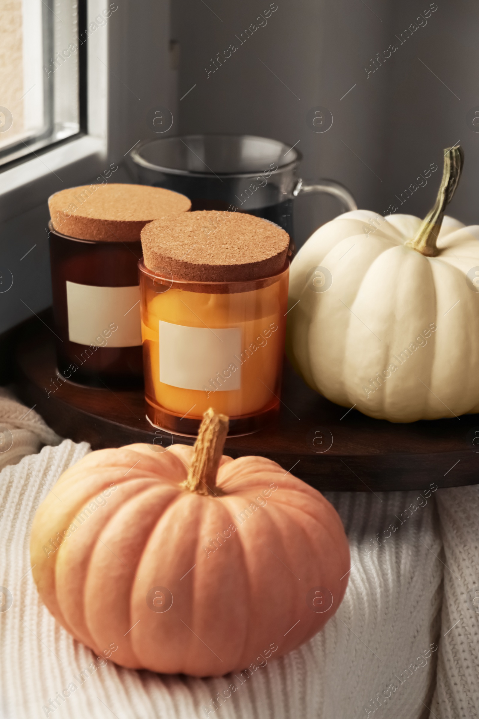 Photo of Beautiful pumpkins and scented candles on window sill indoors