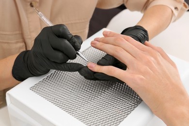 Professional manicurist working with client at white table, closeup