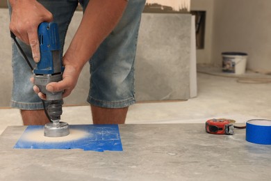 Worker making socket hole in tile indoors, closeup