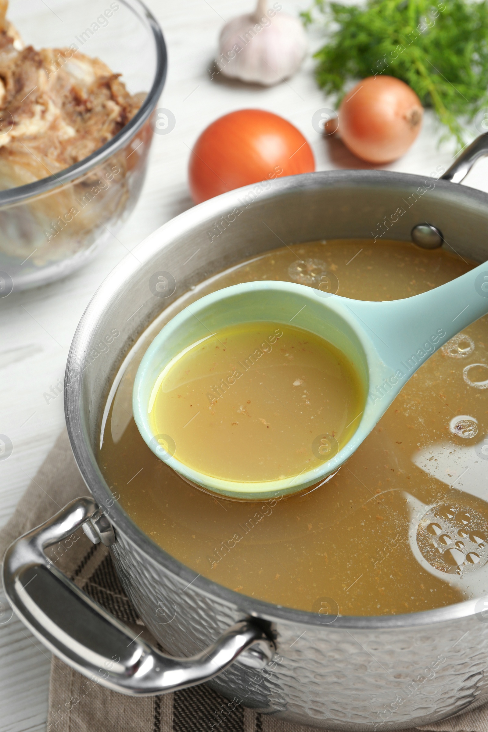 Photo of Delicious homemade bone broth and ingredients on white wooden table