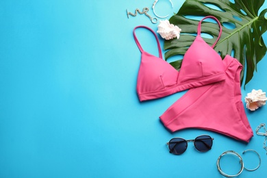 Photo of Beautiful pink bikini and beach accessories on light blue background, flat lay. Space for text