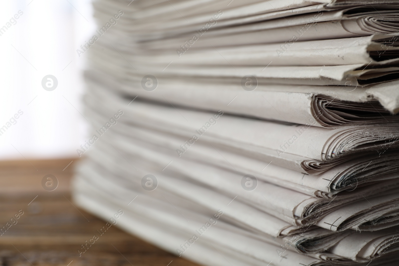 Photo of Stack of newspapers on wooden table, closeup. Journalist's work