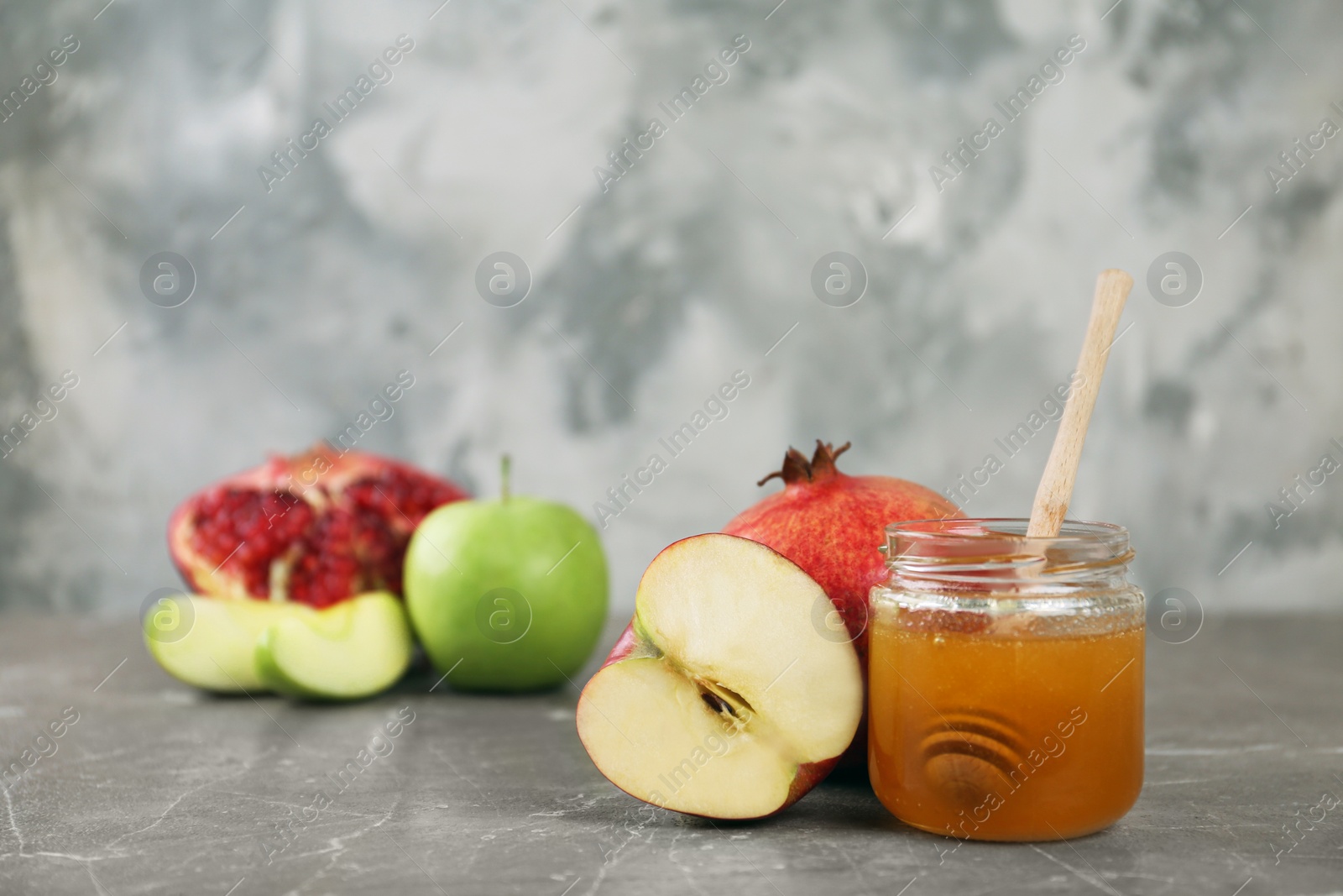 Photo of Honey, apples and pomegranate on marble table. Rosh Hashanah holiday