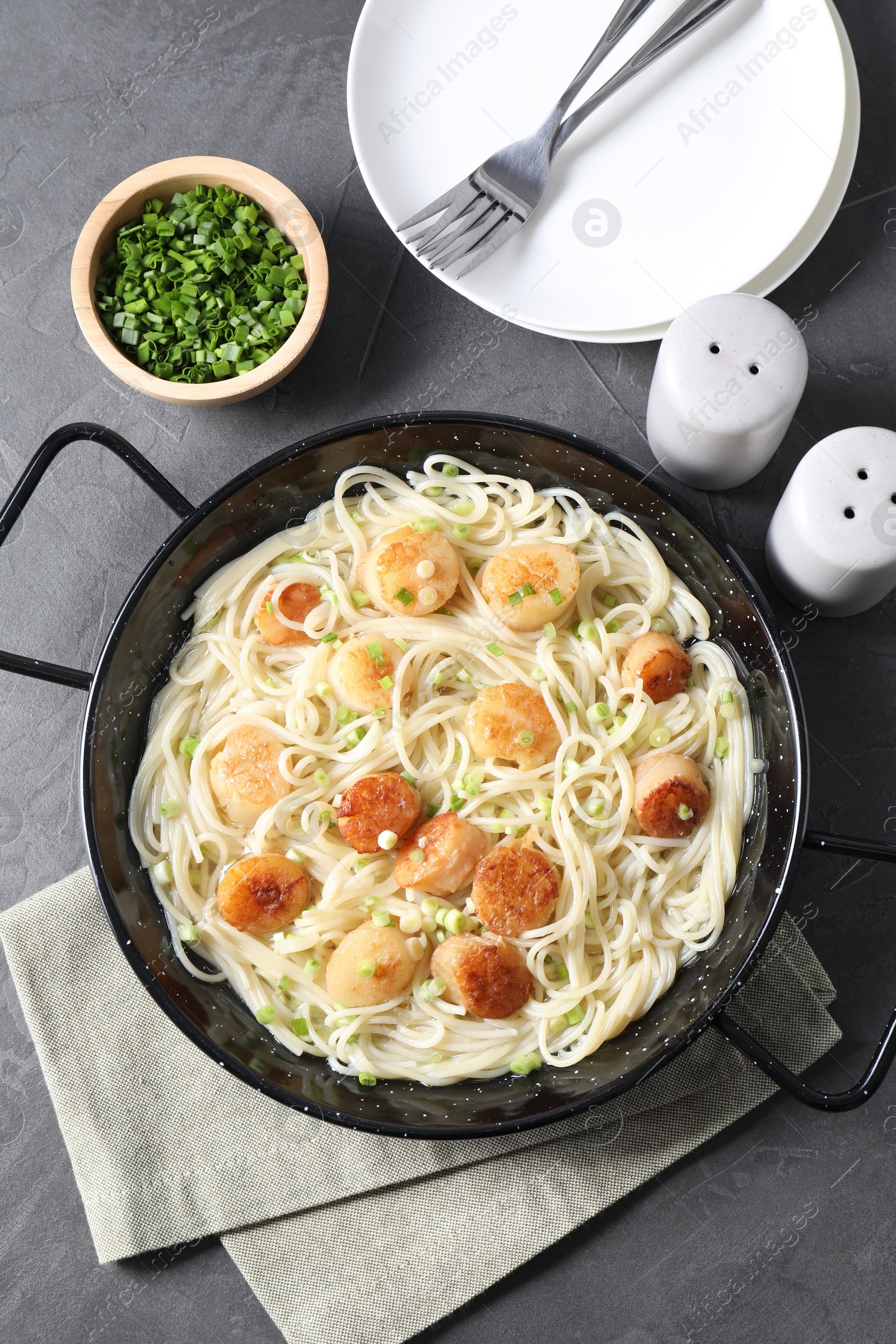 Photo of Delicious scallop pasta with green onion served on grey table, flat lay