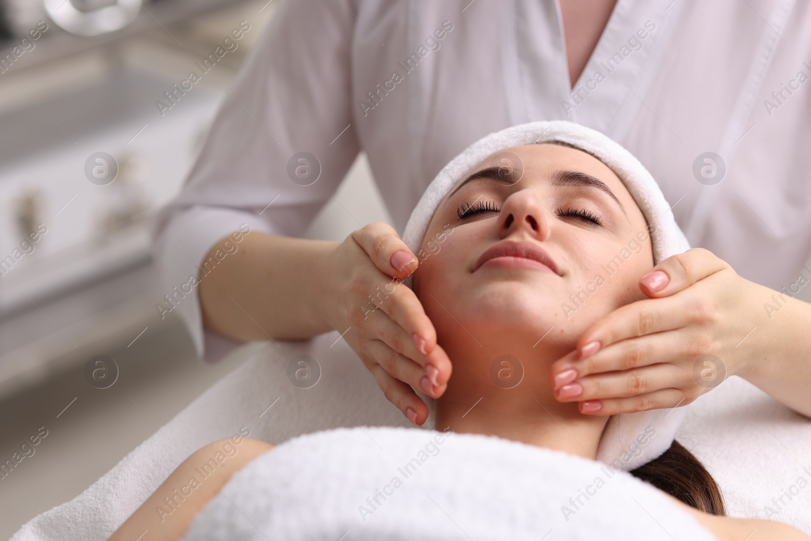 Photo of Cosmetologist making face massage to client in clinic, closeup