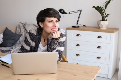 Photo of Young woman working with laptop at desk. Home office