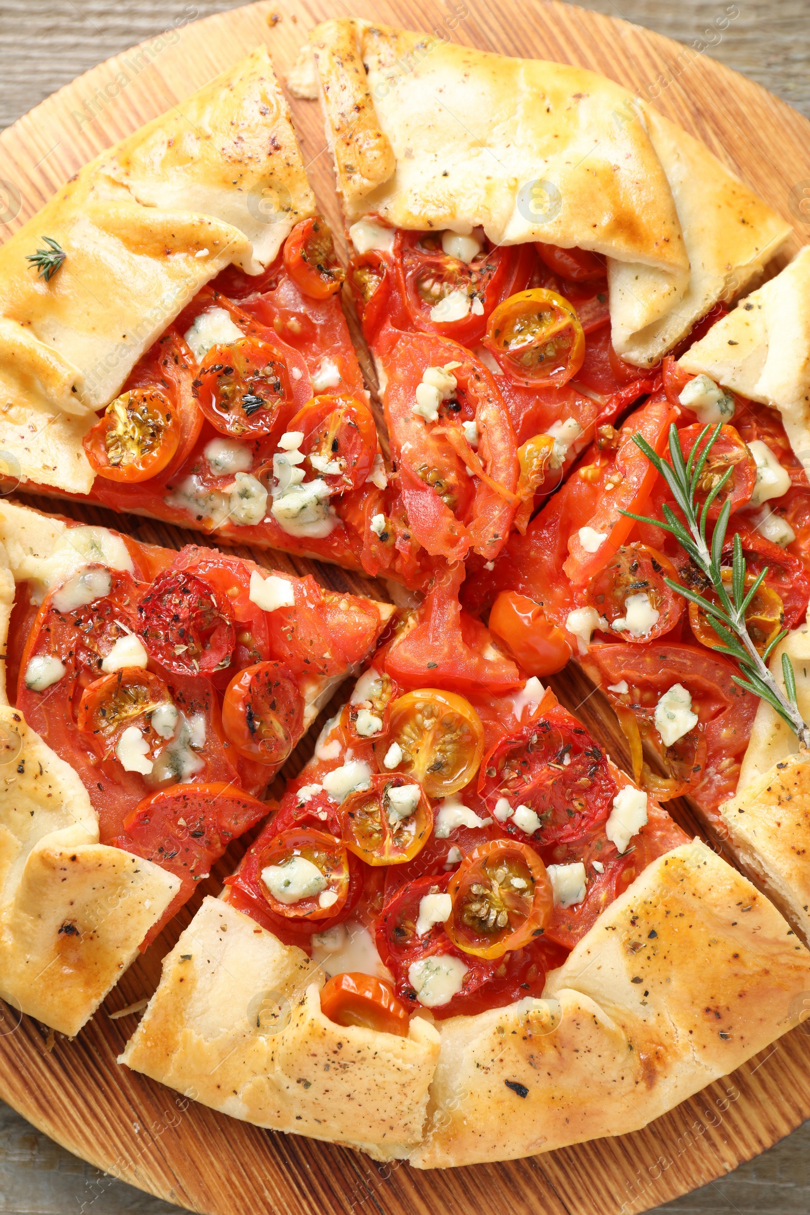 Photo of Tasty galette with tomato, rosemary and cheese (Caprese galette) on wooden table, top view