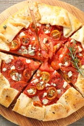 Tasty galette with tomato, rosemary and cheese (Caprese galette) on wooden table, top view