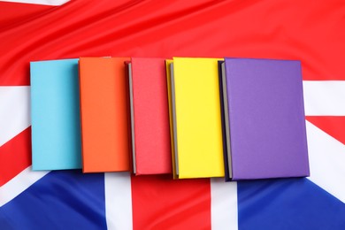 Photo of Learning foreign language. Different books on flag of United Kingdom, top view