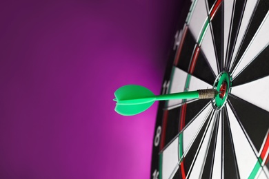 Green arrow hitting target on dart board against purple background