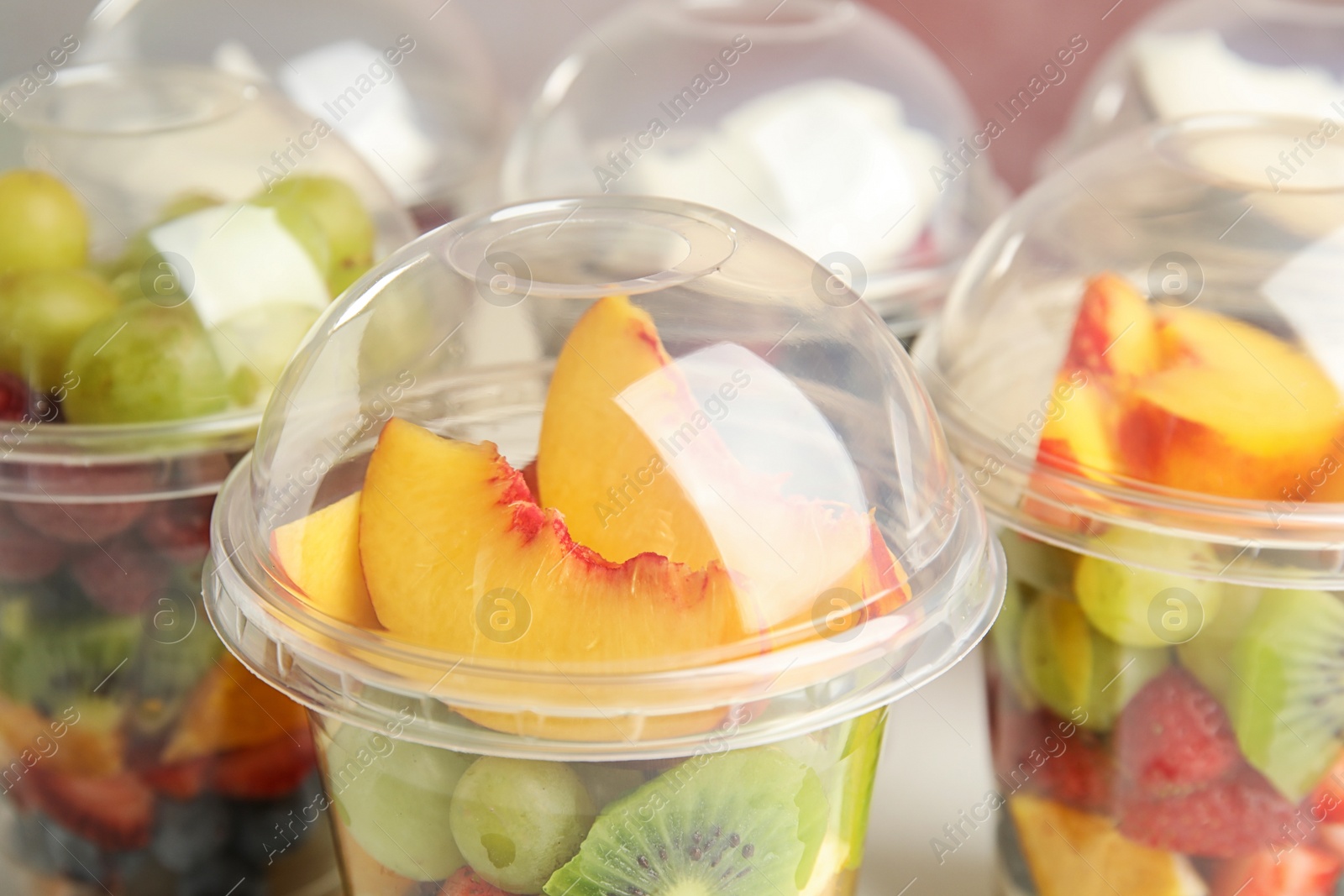 Photo of Fresh tasty fruit salad in plastic cups, closeup