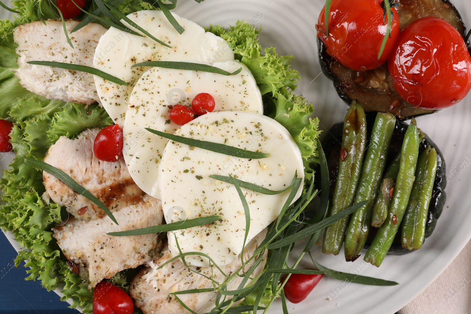 Photo of Tasty mozzarella, chicken and vegetables with tarragon on white plate, top view