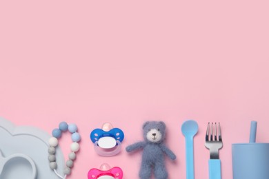 Photo of Flat lay composition with pacifiers and other baby stuff on pink background. Space for text