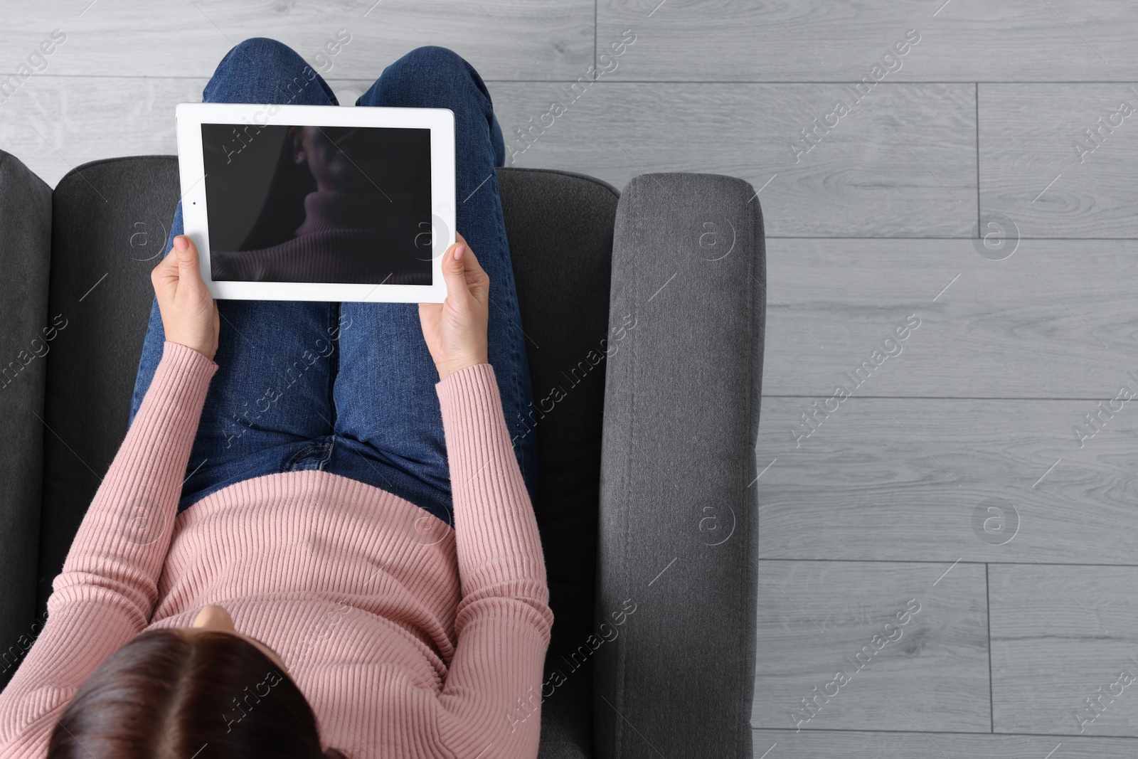 Photo of Woman working with tablet in armchair, top view. Space for text