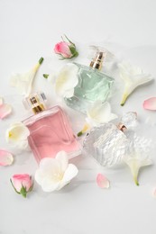 Photo of Luxury perfume and floral decor on white marble table, flat lay