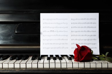 Photo of Beautiful red rose and musical notes on piano
