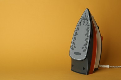 One modern iron on orange background, space for text. Home appliance