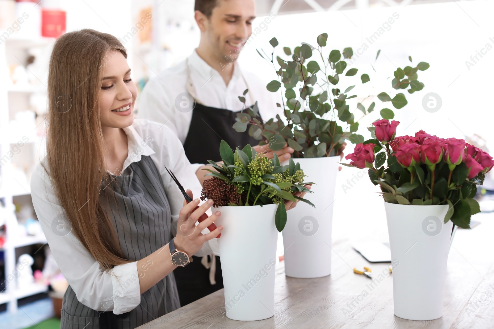 Photo of Young florists making beautiful bouquet in flower shop