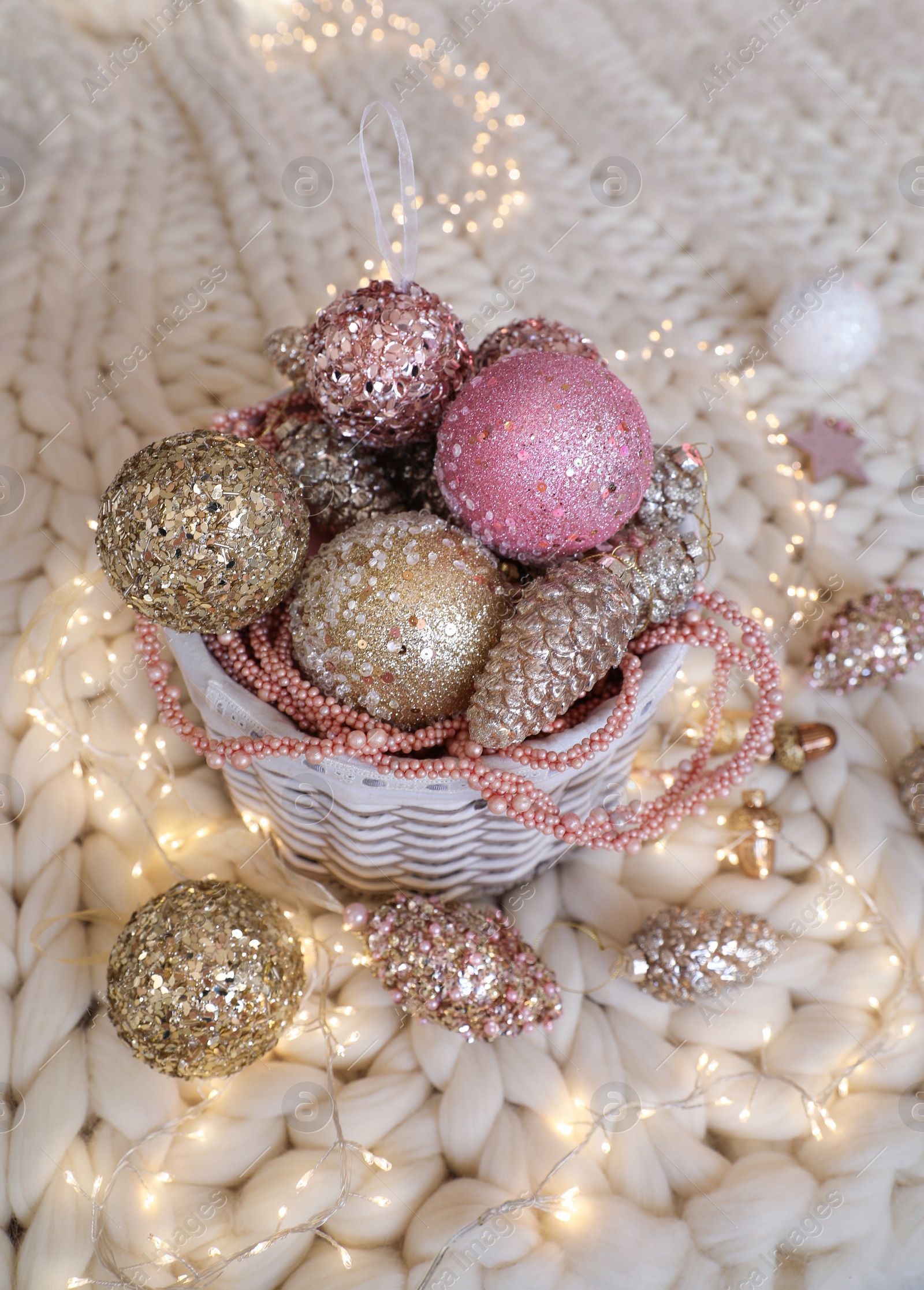 Photo of Beautiful Christmas tree baubles and fairy lights on white knitted fabric