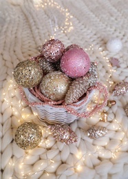 Beautiful Christmas tree baubles and fairy lights on white knitted fabric