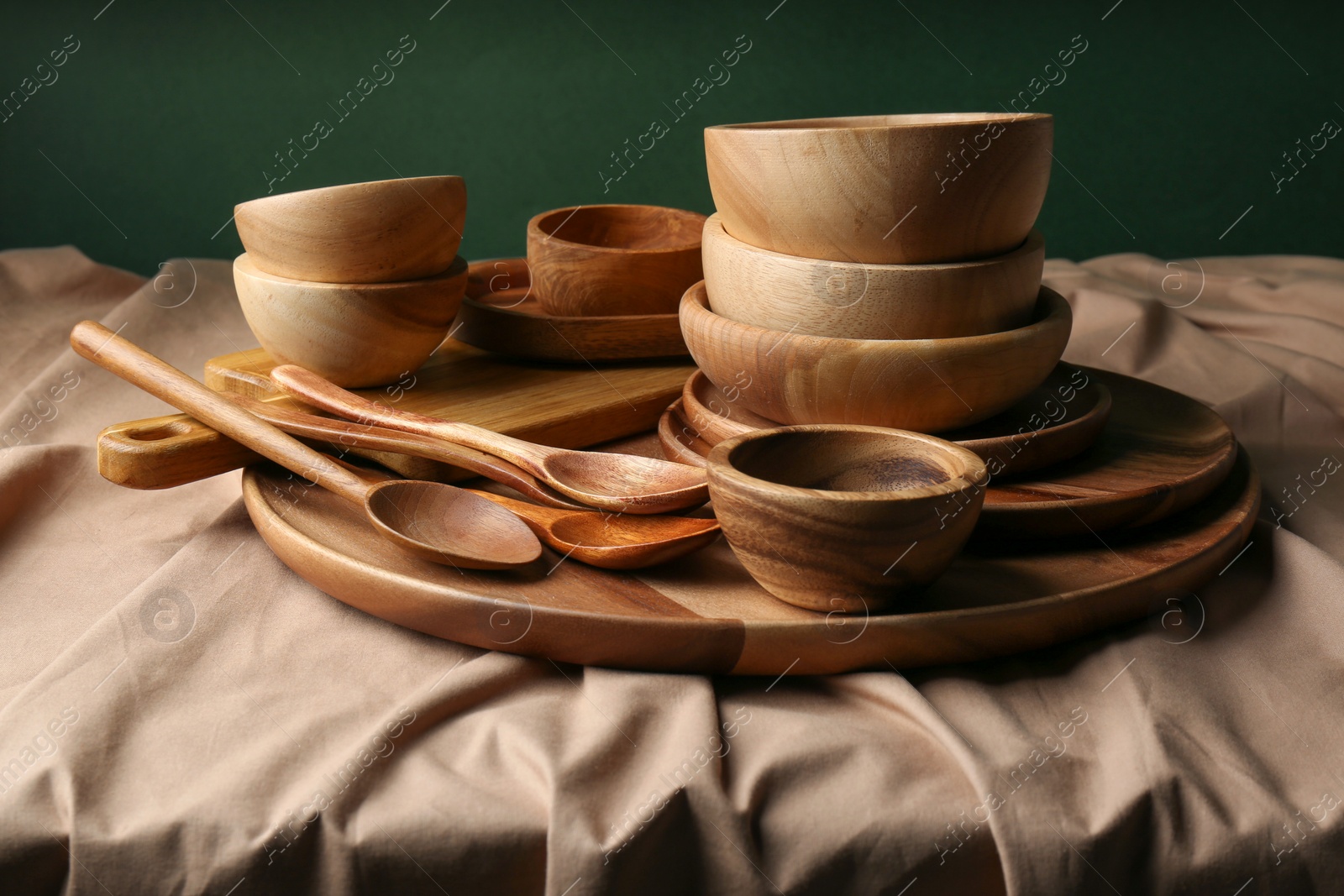 Photo of Set of wooden dishware and utensils on table against green background